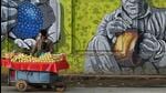 A vendor sells fruits next to a mural wall. (AFP) A vendor sells fruits next to a mural wall. (AFP)