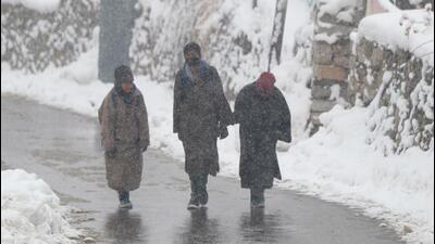 People walk on a snow-covered road in Srinagar on Friday. (ANI Photo) People walk on a snow-covered road in Srinagar on Friday. (ANI Photo)