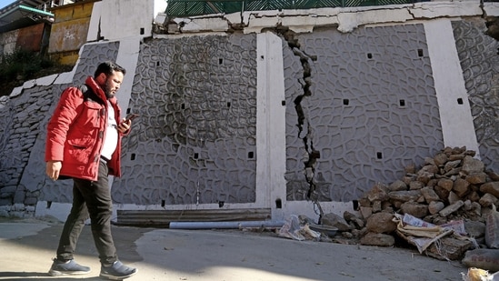 A passerby looks at the rubble of a wall that got damaged due to continuous land subsidence, in Joshimath. (ANI)
