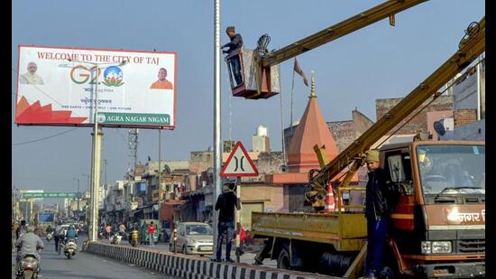 An electrician installs tricolour lights on a street light pole as part of city beautification work ahead of the G20 Summit, in Agra. (PTI Photo)