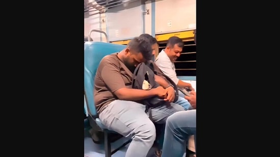 The image, taken from the Instagram video, shows a man riding a train with a puppy in his backpack.(Instagram/@pettownindia)