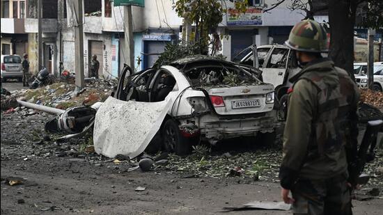 An army soldier near the car ripped apart by a blast in Narwal area of Jammu city on Saturday. (Waseem Andrabi /Hindustan Times)