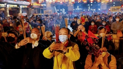 A worshipper wearing a face mask makes an offering of incense sticks ahead of the Lunar New Year, during the coronavirus disease (COVID-19) pandemic in Hong Kong, China, Sunday. (Reuters)