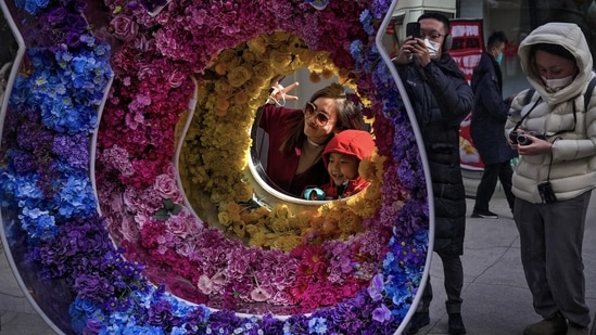 A woman and a child pose a souvenir photo with a rabbit shaped floral decoration at a pedestrian shopping street at Qianmen on the first day of the Lunar New Year holiday in Beijing.(AP)