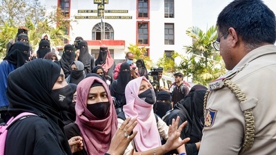 Students wearing burqa and hijab talk to a police officer during their protest, outside the Shivamogga District collector's office, in Shivamogga, February 17, 2022 (PTI) Students wearing burqa and hijab talk to a police officer during their protest, outside the Shivamogga District collector's office, in Shivamogga, February 17, 2022 (PTI)