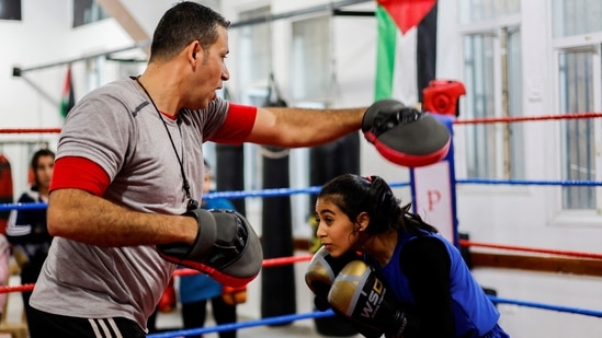 A 15-year-old Palestinian girl, Farah Abu Al-Qomsan, trains with coach Ayoub inside the Palestine Boxing Center, on January 17. "The girls are ready. I trained them hard for five years," Ayoub told Reuters. "We are setting an example." (Mohammed Salem / REUTERS)