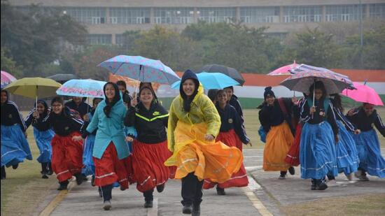 Girls in traditional attire running for cover as it rained during the Republic Day rehearsal in Panchkula on Tuesday. (Sant Arora/HT)