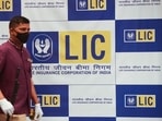 A man walks past a hoarding of Life Insurance Corporation of India (LIC) in Mumbai.