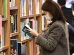 Covid In South Korea: A woman wearing a face mask reads a book at a bookstore in Seoul. Covid In South Korea: A woman wearing a face mask reads a book at a bookstore in Seoul.