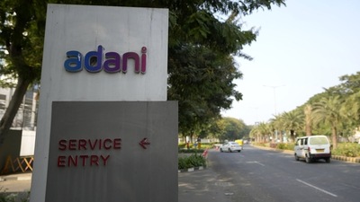 Vehicles move past a signage near the entrance of Adani Corporate House in Ahmedabad, (AP) Vehicles move past a signage near the entrance of Adani Corporate House in Ahmedabad, (AP)