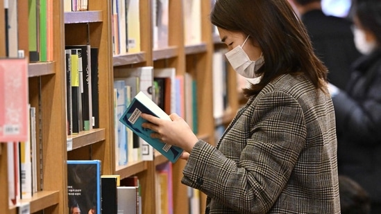 Covid In South Korea: A woman wearing a face mask reads a book at a bookstore in Seoul.(AFP) Covid In South Korea: A woman wearing a face mask reads a book at a bookstore in Seoul.(AFP)