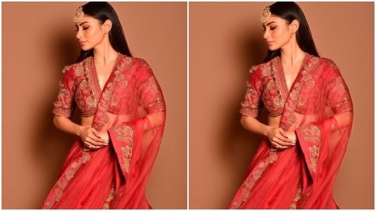 Mouni looked every bit gorgeous in the red silk blouse featuring long sleeves and a plunging neckline, decorated in golden zari details and embroidery work in golden resham threads. (Instagram/@imouniroy)