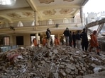 Rescue workers gather as they conduct an operation to clear the rubble and search for bodies at the site of Monday's suicide bombing, in Peshawar, Pakistan, Tuesday.