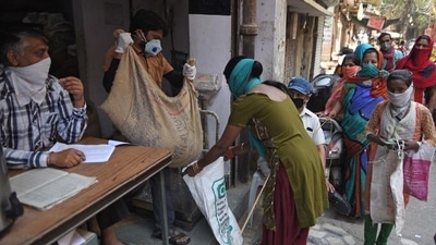 People queue up to take foodgrains from a government PDS shop in New Delhi. (HT file)