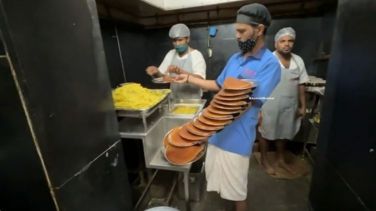 A screengrab from the video shared by Anand Mahindra. It shows the waiter balancing several plates on his hand, from palm to arm. (Twitter/@anandmahindra)