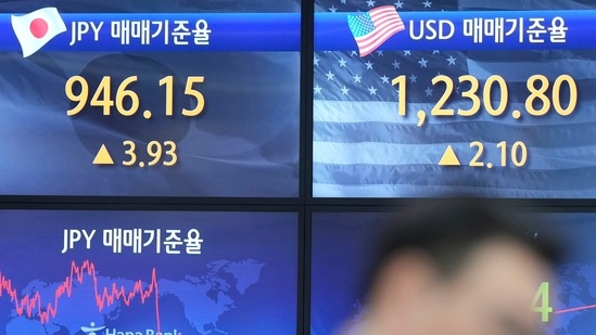 A currency trader walks by the screens showing the foreign exchange rates at a foreign exchange dealing room in Seoul, South Korea, Wednesday, Feb. 1, 2023. (AP)