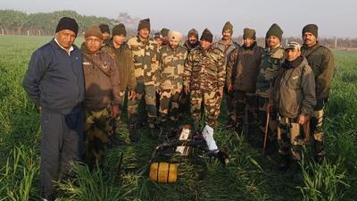 Border Security Force personnel with the drone that was shot down near Rear Kakkar border outpost in Amritsar district on Friday. The drone was carrying 5kg of heroin, which was also recovered. (HT Photo)