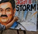 An artist gives final touches to a painting of Gautam Adani, depicting the ongoing crisis of the Adani group, in Mumbai, (AP)