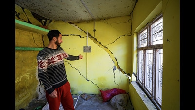 A resident shows cracks that have appeared in his house in Nai Basti area, in Doda district on Saturday. (PTI) A resident shows cracks that have appeared in his house in Nai Basti area, in Doda district on Saturday. (PTI)