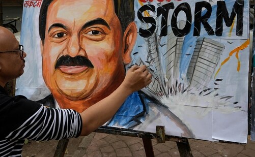 An artist gives final touches to a painting of Gautam Adani, depicting the ongoing crisis of the Adani group, in Mumbai, (AP)