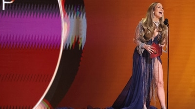 Jennifer Lopez, who presented the Grammy award to Harry Styles, stuns on the stage in a gorgeous purple embellished gown featuring a low neckline, front thigh-high slit, shimmering tassels, and embellished sleeves. She rounded it all off with high heels, diamond jewellery and open hair.&nbsp; (REUTERS)