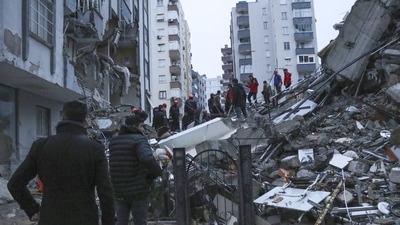 People and rescue teams try to reach trapped residents inside collapsed buildings in Adana, Turkey. (AP)