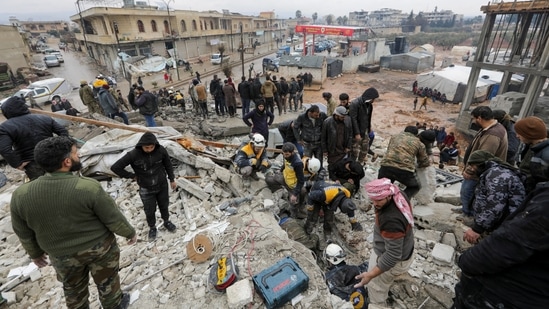 People gather as rescuers search for survivors under the rubble, following an earthquake, in rebel-held town of Jandaris, Syria. (REUTERS)