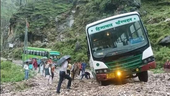 A Himachal Road Transport Corporation (HRTC) bus stuck in debris following a flashflood after heavy rain at Talehan in Karsog sub division of Mandi district on Thursday. (HT Photo)