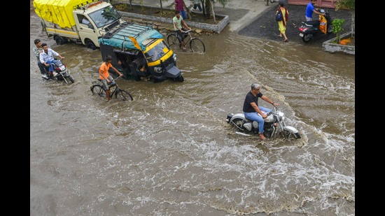 Commuters wade through a flooded road after rains in Jalandhar on Thursday. (PTI)