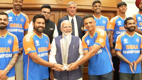 PM Modi holds the T20 World Cup trophy as the Indian cricketers sport a smile