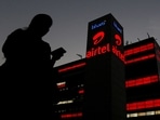 A girl checks her mobile phone as she walks past the Bharti Airtel office building in Gurugram, on the outskirts of New Delhi.