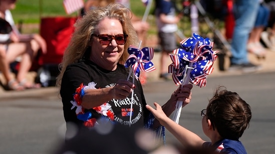 A woman hands out patriotic pinwheels during the Colorado 4th at Firestone parade to mark the Independence Day holiday Thursday, July 4, 2024, in Firestone, Colo. Floats, marching bands, classic cars and motorcycles were features in the annual parade through the Weld County community north of Denver.(AP/David Zalubowski)