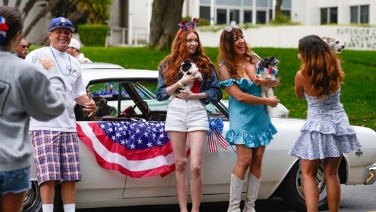Members of Love Leo Rescue, a local animal rescue service, take pictures before riding a vintage car with their dogs at the Santa Monica 4th of July parade in Santa Monica, Calif., on Thursday, July 4, 2024.&nbsp;(AP/Damian Dovarganes)