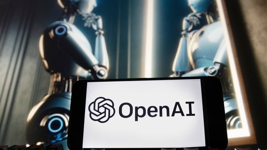 The OpenAI logo is displayed on a cell phone with an image on a computer monitor generated by ChatGPT's Dall-E text-to-image model.(AP)
