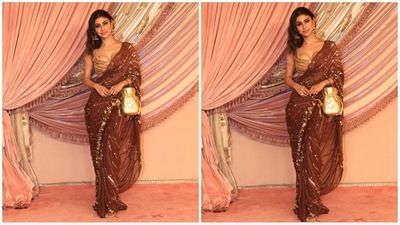 Mouni Roy dazzled in a stunning brown saree, embellished with intricate golden sequins and heavily adorned borders. She paired the saree with a golden bralette blouse, statement earrings, and a shiny gold potli bag, completing her glam look with flair. (HT photo/VarinderChawla) Mouni Roy dazzled in a stunning brown saree, embellished with intricate golden sequins and heavily adorned borders. She paired the saree with a golden bralette blouse, statement earrings, and a shiny gold potli bag, completing her glam look with flair. (HT photo/VarinderChawla)