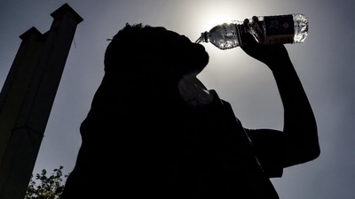 A passenger drinking water is silhouetted against the sun on a hot summer day at Jalandhar Cantonment railway station in Jalandhar on June 11, 2024 amid heatwave. (113 degrees Fahrenheit). (Photo by Shammi MEHRA / AFP) (AFP) A passenger drinking water is silhouetted against the sun on a hot summer day at Jalandhar Cantonment railway station in Jalandhar on June 11, 2024 amid heatwave. (113 degrees Fahrenheit). (Photo by Shammi MEHRA / AFP) (AFP)