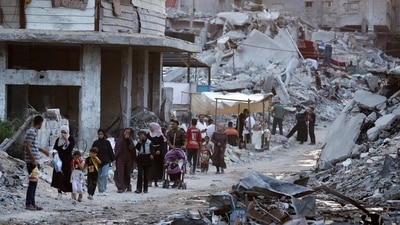 Palestinians displaced by the Israeli air and ground offensive on the Gaza Strip walk next to a dark streak of sewage flowing into the streets of the southern town of Khan Younis, Gaza Strip (AP)