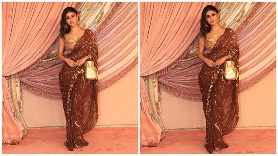 Mouni Roy dazzled in a stunning brown saree, embellished with intricate golden sequins and heavily adorned borders. She paired the saree with a golden bralette blouse, statement earrings, and a shiny gold potli bag, completing her glam look with flair.(HT photo/VarinderChawla)