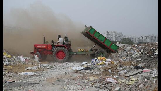 A tractor driver illegally dumping construction waste on an empty plot of land in Sector 52A in Gurugram. (Parveen Kumar/HT PHOTO)