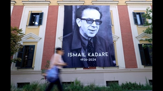 A woman walks by a banner with a portrait of renowned Albanian writer Ismail Kadare on the second day of national mourning following his death on July 1 2024, in Tirana, on July 3, 2024. (Photo by ADNAN BECI / AFP) (AFP)