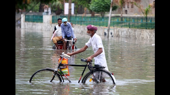 Commuters wade through a waterlogged road on the Power House road in Bathinda on Saturday. (Sanjeev Kumar/HT)