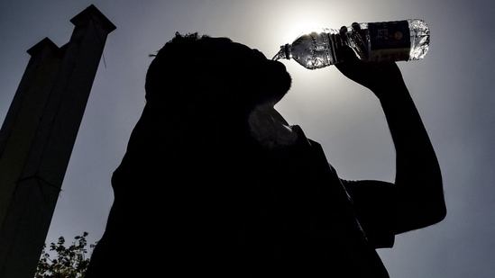 A passenger drinking water is silhouetted against the sun on a hot summer day at Jalandhar Cantonment railway station in Jalandhar on June 11, 2024 amid heatwave. (113 degrees Fahrenheit). (Photo by Shammi MEHRA / AFP)(AFP)