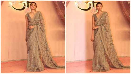 Athiya Shetty exudes sartorial elegance in a beautifully cream-hued saree adorned with floral embellishments and lace borders. She paired it with a V-neck blouse, statement earrings, kohl-rimmed eyes, and red lips, completing her head-turning look.(HT photo/VarinderChawla)