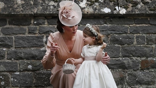 Britain's Catherine, Duchess of Cambridge (L) speaks to her daughter Britain's princess Charlotte, a bridesmaid, following the wedding of her sister Pippa Middleton to James Matthews at St Mark's Church in Englefield, west of London, on May 20, 2017. (KIRSTY WIGGLESWORTH / AFP)