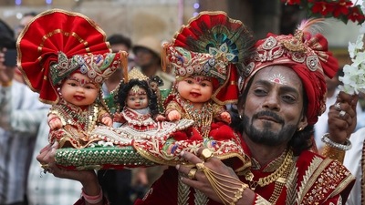 A devotee carries idols of Hindu Lord Jagannath, his sister Subadhra and brother Balabhadra, as he arrives to attend the annual Rath Yatra, or chariot procession, in Ahmedabad, ((Amit Dave, Reuters))