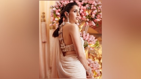 For her third look, Shloka chose a pearl white saree from the renowned Australian designer Tamara Ralph. The pre-draped nine yeards features floral embellishments on the hem, bead embellishments on the floor-sweeping pallu, and a tailored fitting. She styled it with a halter-neck blouse adorned with pearl embellishments, intricate silver sequin embroidery, and crystal-studded bow buttons on the back. (Instagram)