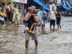 A man carries two children in Chunabhatti's Swadeshi Mill Chawl, flooded by last night's rains. HT Photo Raju Shinde A man carries two children in Chunabhatti's Swadeshi Mill Chawl, flooded by last night's rains. HT Photo Raju Shinde