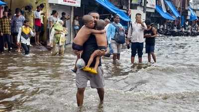 A man carries two children in Chunabhatti's Swadeshi Mill Chawl, flooded by last night's rains. HT Photo Raju Shinde