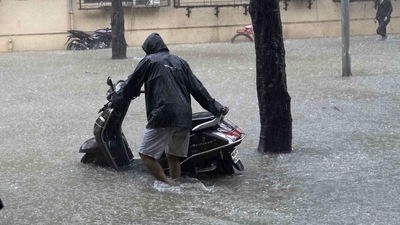 A man wades through a waterlogged road with his scooty at Taloja MIDC in Navi Mumbai.  (Bachchan Kumar/ HT PHOTO)