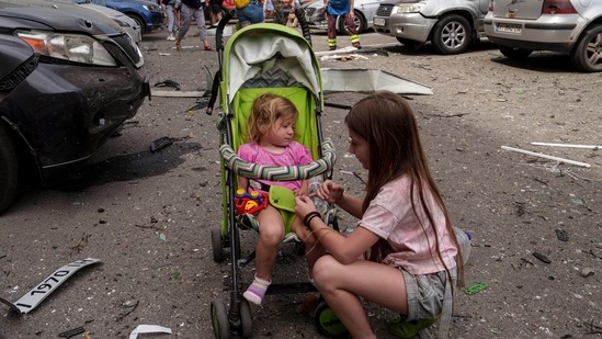 Children wait near the site of Okhmatdyt children’s hospital hit by Russian missiles, in Kyiv, Ukraine, Monday, July 8, 2024. Russian missiles have killed at least seven people and struck a children’s hospital in the Ukrainian capital, Kyiv, authorities say. (AP Photo/Evgeniy Maloletka)